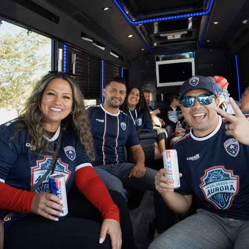 Group boarding a white charter bus for Sporting Event Transportation transportation in Aurora